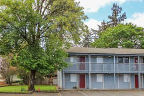 Puyallup apartment for rent - A tree in front of a grey building with red doors.