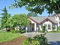 Lakewood apartment for rent - A white building with a red roof is surrounded by greenery.