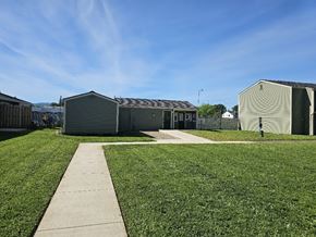 Lebanon apartment for rent - A grassy area with a concrete walkway leading to a building with a grey roof.