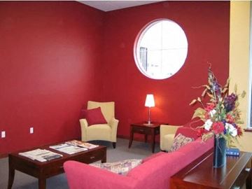 Hillsboro apartment for rent - A living room with a pink couch, a yellow chair, a coffee table, and a round window.