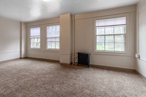 Olympia apartment for rent - A room with a carpeted floor, two windows, and a radiator.
