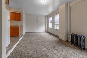 Olympia apartment for rent - A spacious room with a carpeted floor and a radiator on the wall.