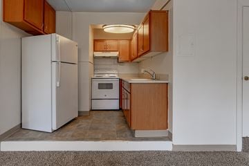 Olympia apartment for rent - A kitchen with a white refrigerator and wooden cabinets.