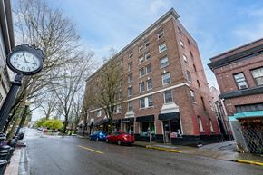 Olympia apartment for rent - A street view of a brick building with a clock on a pole.