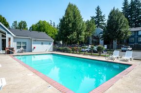 Tualatin apartment for rent - A swimming pool surrounded by a concrete patio and a black fence.