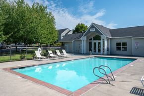 Portland apartment for rent - A pool with a diving board and lounge chairs in front of a building.