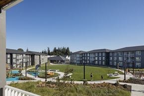 St Helens townhouse for rent - A view of apartment buildings with a pool and playground.