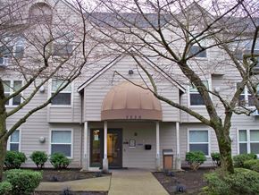 Portland apartment for rent - the front of a white house with a sidewalk and trees
