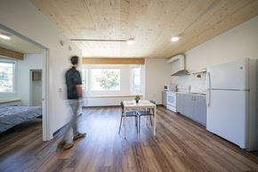 Portland apartment for rent - a man walking through a kitchen with a table and a refrigerator