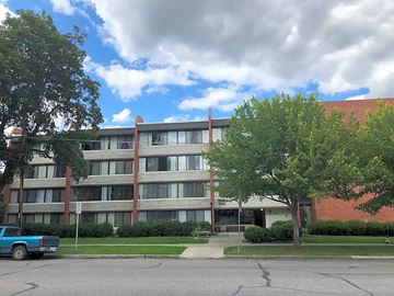 Spokane apartment for rent - A large building with a red roof and a blue truck parked in front.
