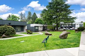 Portland apartment for rent - A park with a bench and a few rocks in the foreground and a building in the background.
