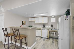 Los Ranchos De Albuquerque apartment for rent - A kitchen with a white refrigerator and wooden chairs.