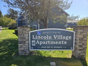 Lincoln City apartment for rent - A sign for Lincoln Village Apartments stands in front of a building.