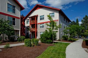 Beaverton apartment for rent - A modern building with a red roof and a white facade with a red stripe down the center.