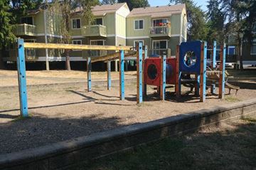 Renton apartment for rent - A playground with a blue swing set and red and blue play equipment.