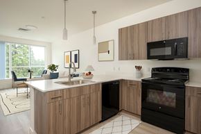 Beaverton apartment for rent - A modern kitchen with wooden cabinets and black appliances.