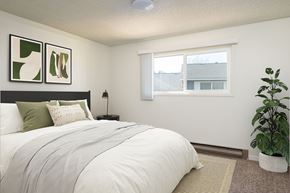 Milwaukie apartment for rent - A bedroom with a large bed and a potted plant.