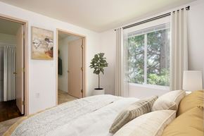 Hillsboro apartment for rent - A bedroom with a large bed and a window with a view of trees.