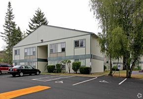 Everett apartment for rent - A parking lot in front of a grey building with a black car parked in the spot.