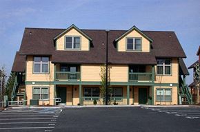 Sandy apartment for rent - a large yellow house with a parking lot