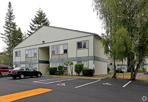Everett apartment for rent - A parking lot in front of a grey building with a black car parked in the spot.