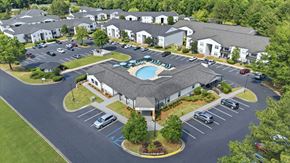 Alabaster apartment for rent - A large building with a pool in the middle of a parking lot.