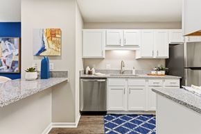 Alabaster apartment for rent - A kitchen with white cabinets and a blue rug.