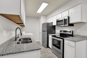 Cordova apartment for rent - a renovated kitchen with stainless steel appliances, granite coutnertops, and white cabinets at Rock Creek