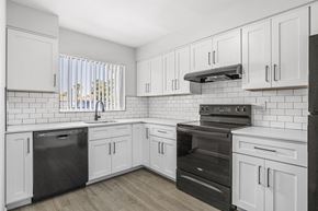 Sarasota apartment for rent - A kitchen with white cabinets and black appliances.