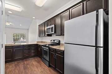 Fairhope apartment for rent - A modern kitchen with dark brown cabinets and a white refrigerator.