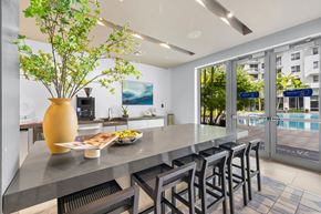 Hallandale Beach apartment for rent - A kitchen with a table and chairs and a vase with a plant in it.