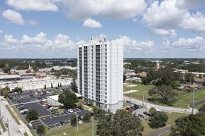 Winter Haven apartment for rent - A tall white building with a parking lot in front of it.