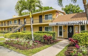 Sarasota apartment for rent - a yellow building with a leasing office and palm trees
