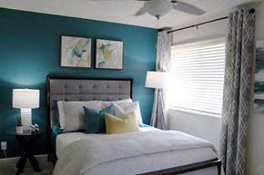 Huntsville apartment for rent - bedroom with large window, modern ceiling fan, teal accent wall and model furnishings  at Huntsville Landing Apartments, Huntsville, Alabama