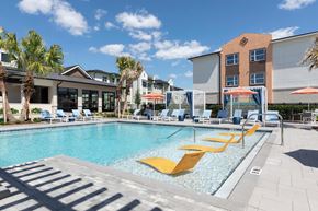 Orlando apartment for rent - A pool with yellow sun loungers and a building in the background.