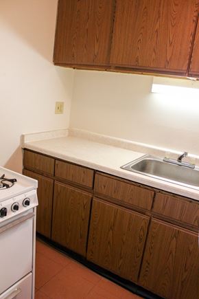 Milwaukee apartment for rent - A white stove is in a kitchen with brown cabinets.