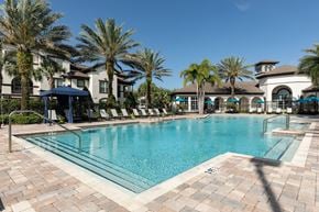 Orlando apartment for rent - a large swimming pool with palm trees in front of a building
