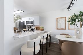 West Palm Beach apartment for rent - A kitchen with white cabinets and a counter with chairs around it.