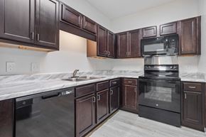 Augusta apartment for rent - a kitchen with dark wood cabinets and black appliances