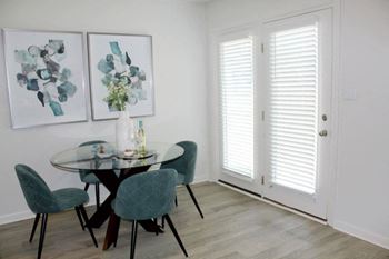 A dining room with white walls and a glass table