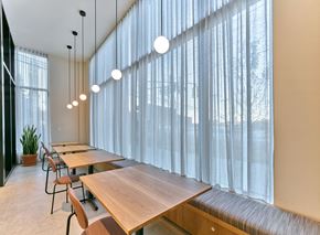 Jersey City apartment for rent - a dining room with long wooden tables and chairs and windows with white curtains