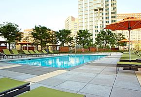 Jersey City apartment for rent - a swimming pool with chaise lounge chairs and umbrellas in front of a large building
