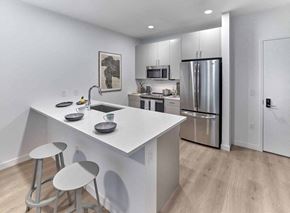 Jersey City apartment for rent - a kitchen with white cabinetry and a large white island with two stools