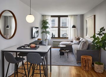 Hoboken apartment for rent - A modern living room with a dining table and grey couch.