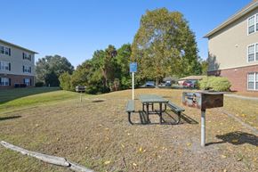 New Bern apartment for rent - A picnic table is in the middle of a grassy area with a sign in the background.