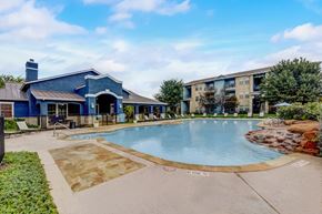 Kyle apartment for rent - A blue building with a pool in front.