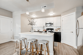 Sandy apartment for rent - A kitchen with white cabinets and a white island with bar stools.