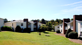A grassy area in front of a building with a bench in the middle.