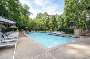 Marietta apartment for rent - A large outdoor swimming pool surrounded by trees and lounge chairs.