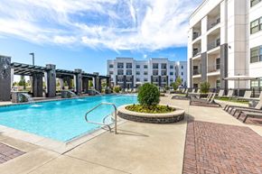 Louisville apartment for rent - A swimming pool surrounded by a brick walkway and a small garden in the middle of a residential area.